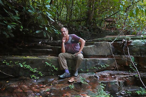 Pascal Héni sitting on the slab in a forest stream just above the rheophytic fern Thelypteris calcarata, Makandawa, Kitulgala, Sri Lanka, Nov. 2024