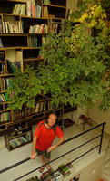 Patrick Blanc at home under bookshelves and blooming Schefflera heterophylla, Sept.2016