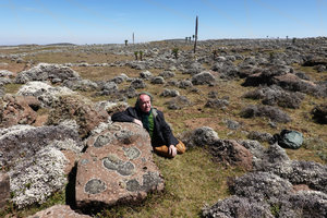 Patrick Blanc behind a stone covered by lichens in the afroalpine steppe with Lobelia rhynchopetalum and Helichrysum citrispinum, Sanetti Plateau, Bale NP, Ethiopia, Jan. 2019