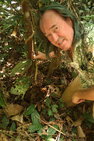 Patrick Blanc holding the stem of Medinilla mirabilis with dense purple baccate fruits congested at the stem base, Matomb, Yaounde, Cameroon, March 2018