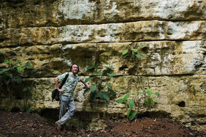 Patrick Blanc leaning on a horizontally layered karst cliff partly covered by climbing Syngonium, Aguateca, Petexbatun, Peten, Guatemala, Jan. 2020