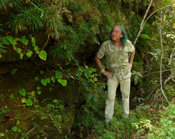 Patrick Blanc looking at the population of a monophyllous Begonia with yellow flowers on a shaded humid rock, Cano Cristales, Meta, Colombia, Oct. 2016