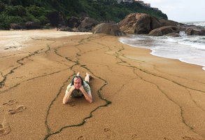 Patrick Blanc lying between ribbons of broken Zostera marina leaves thrown on the beach sand, Hue, Vietnam, Oct. 2018