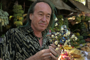 Patrick Blanc observing the blackish sepals and bright white stamens of Clematis smilacifolia sold as a bouquet on local market, Mount Popa, Mandalay, Myanmar, Dec. 2017