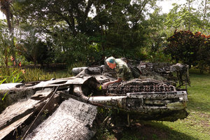 Patrick Blanc observing the roots of a fern growing in a World War 2 aircraft carcass, Vilu Museum, Guadalcanal, Solomon Islands, Sept. 2019