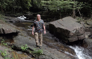 Patrick Blanc on slabs of rapids, the fast flowing river habitat of the rheophytic Curcuma albiflora, Makandawa, Kitulgala, Sri Lanka, Nov. 2024
