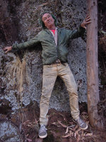 Patrick Blanc standing against a lichen covered vertical rock, Lake Titicaca, Peru, Aug 2014