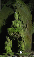 Statue covered in green algae at cave entrance, Yamaguchi, Japan
