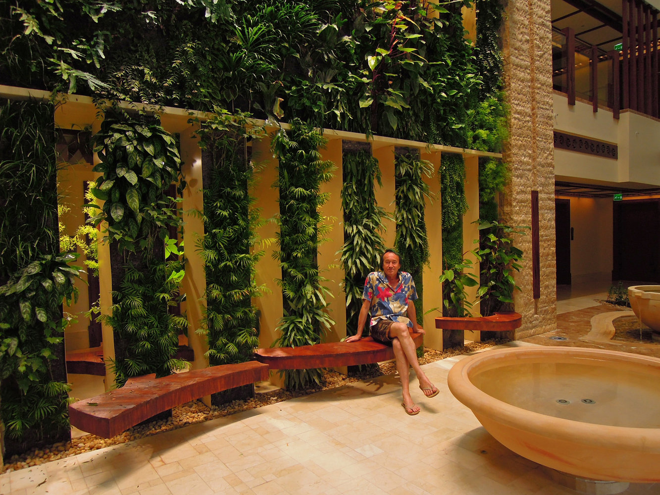 Patrick Blanc sitting on a wooden bench in front of the Beach Suites